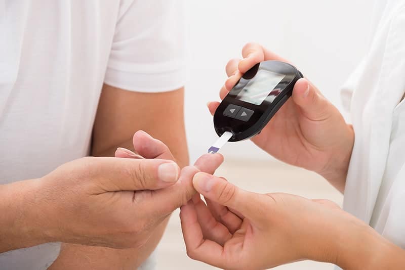 Doctor Using Glucometer On Patient's Finger to check blood sugar