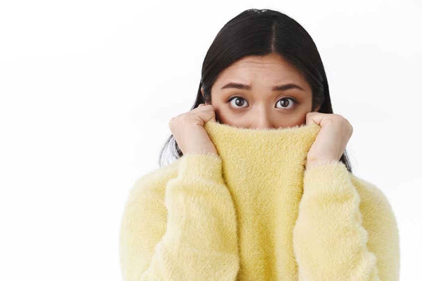 young adult woman shy and hiding in her sweater
